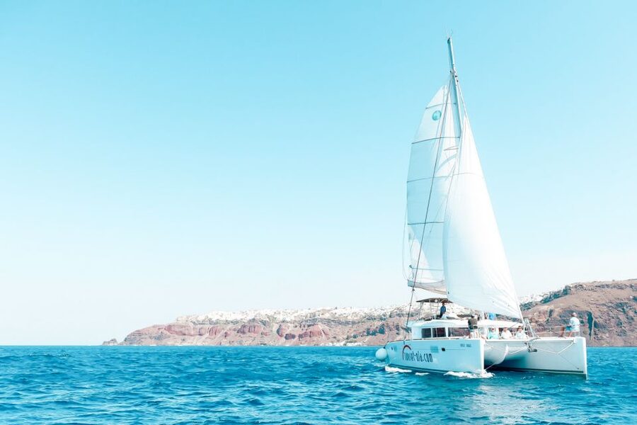Santorini: Catamaran Tour with BBQ Meal and Unlimited Drinks - The sunset cruise beneath Oia