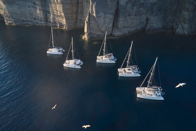 Santorini: Luxury Catamaran Cruise with Fresh Fish BBQ & Drinks - The lighthouse and southern tip of Santorini